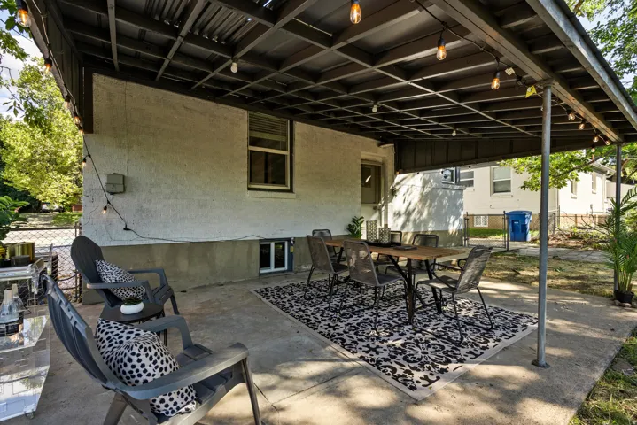 Concrete patio with an overhead pergola structure and string lighting