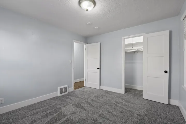 Room featuring grey patterned carpeting, light blue wall paint, white trim, and a white ceiling light fixture
