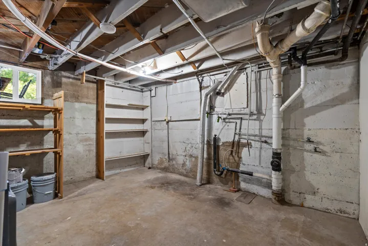 Unfinished basement area featuring exposed ceiling joists and concrete flooring