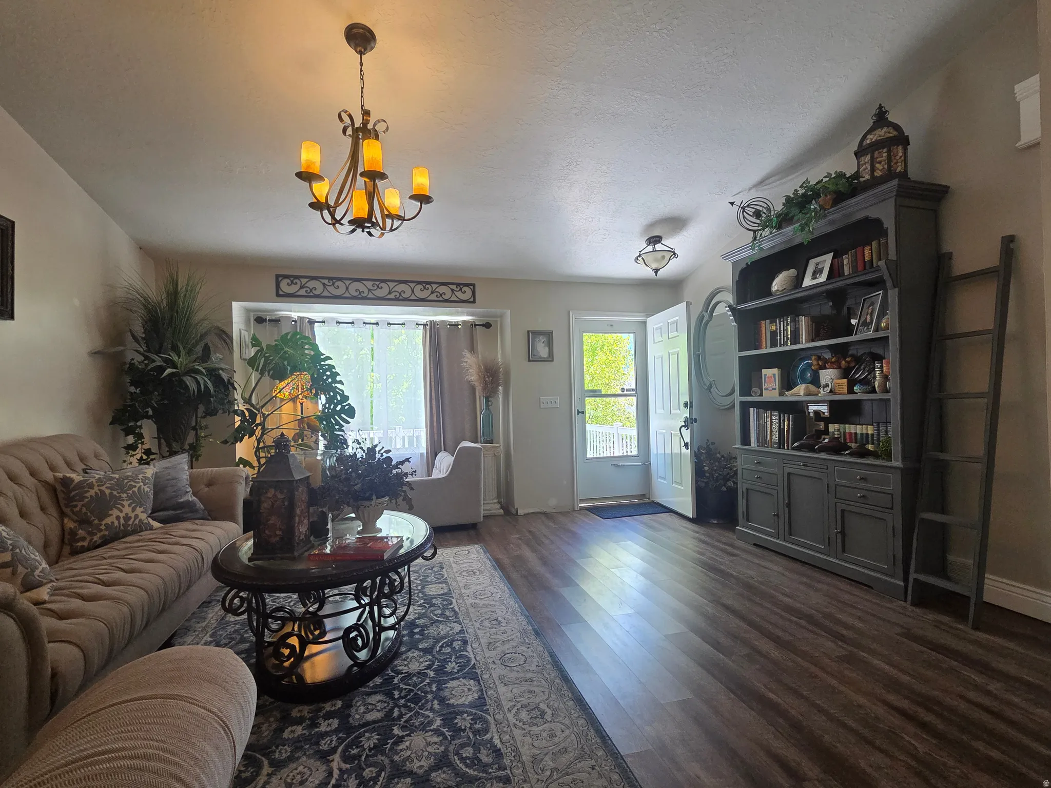 Spacious living area featuring wood-finish flooring, a decorative chandelier, and a built-in shelving unit