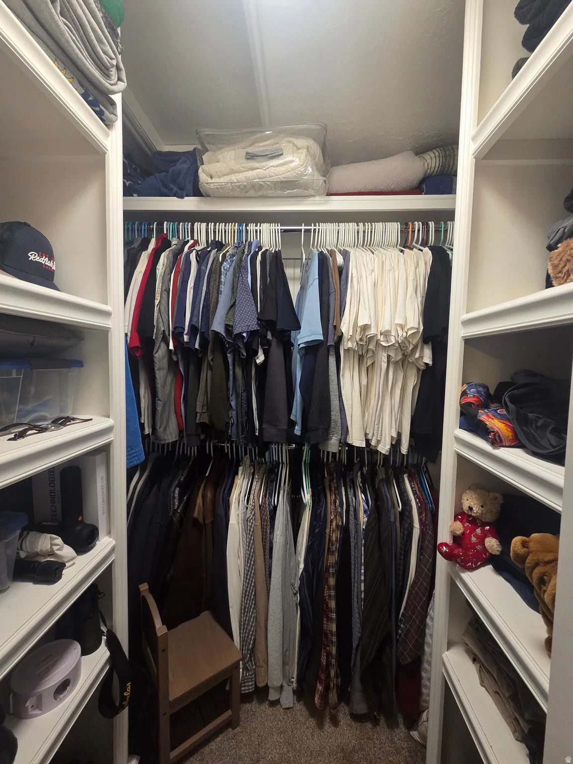 Walk-in closet featuring built-in shelving, multiple hanging rods, and plush carpet flooring