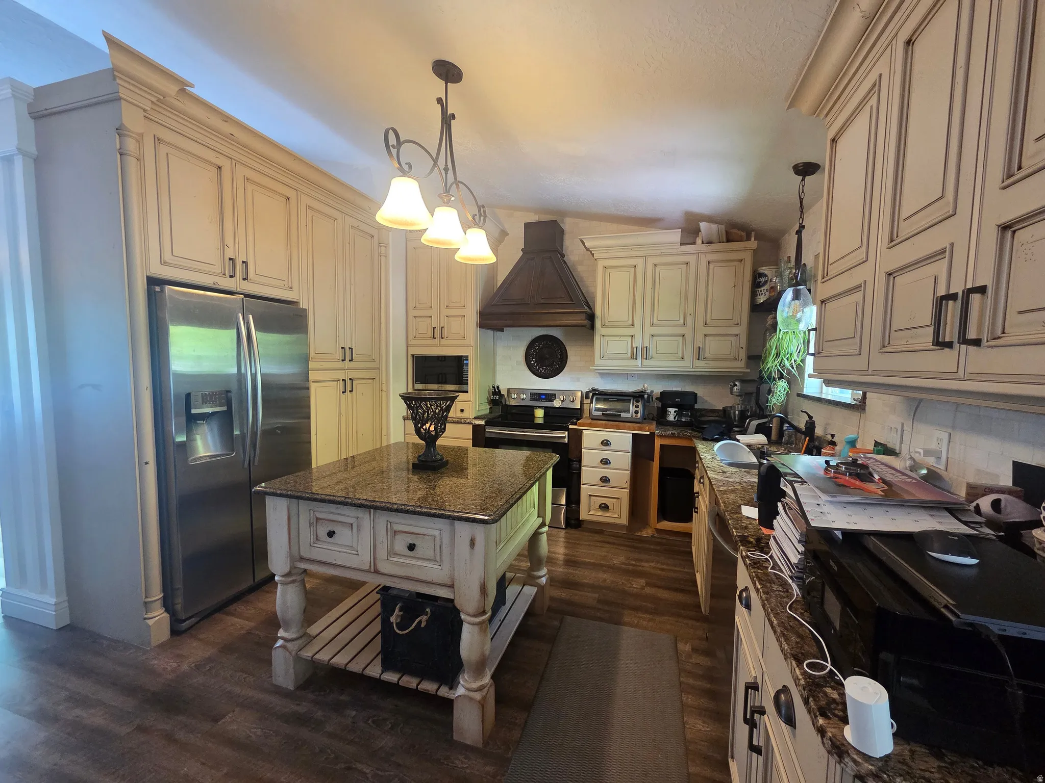 Kitchen featuring extensive cream-finished cabinetry, stainless steel appliances, a freestanding island with a granite-style countertop, and wood-finish flooring