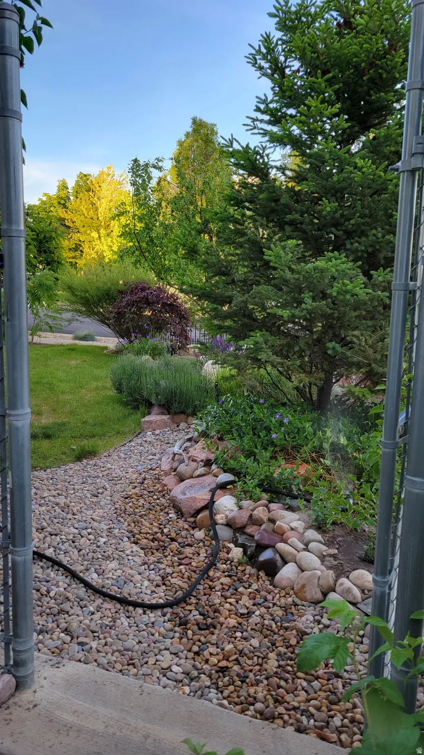 Landscaped exterior featuring a gravel path, decorative river rocks, and mature trees