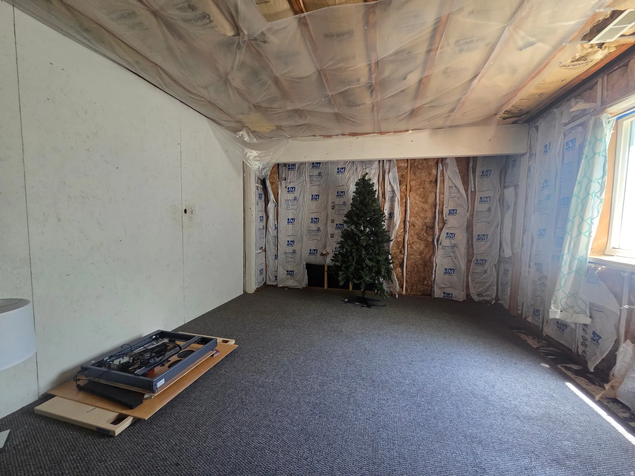 Unfinished basement space featuring a window, exposed framing, and installed carpeting