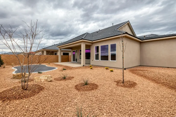 Stucco exterior featuring multiple large windows and a covered patio