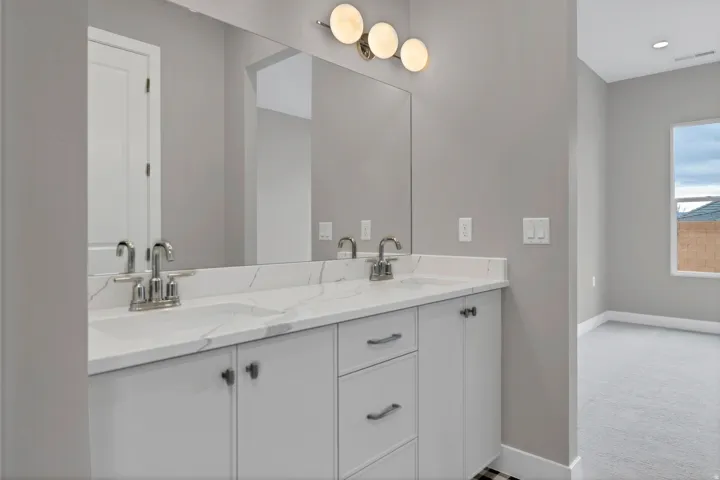 Double vanity with white cabinetry, polished chrome fixtures, and a large mirror