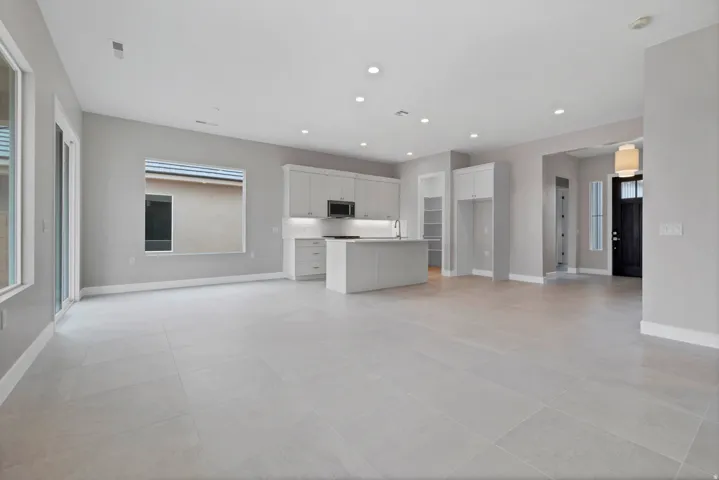 Open-concept living space with large format tile flooring and recessed lighting