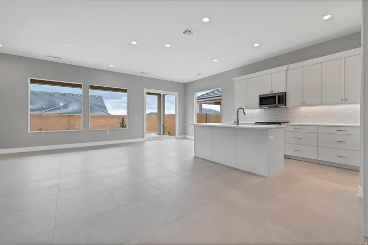 Spacious open-concept living area featuring a modern kitchen with a central island, stainless steel appliances, and subway tile backsplash