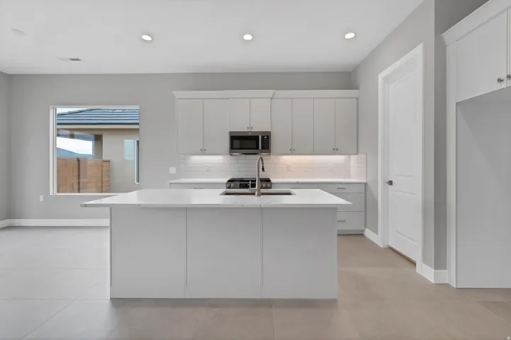 Modern kitchen with a large center island featuring a sink and a stainless steel faucet