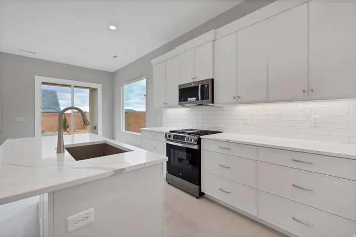 Modern kitchen featuring an island with an undermount sink and gooseneck faucet