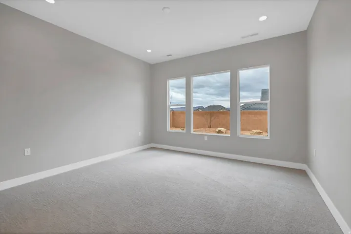 Spacious room featuring three large windows, light gray carpet, recessed lighting, and white baseboards