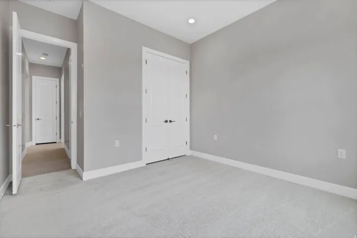 Room featuring light gray wall paint, white trim, and a textured gray carpet
