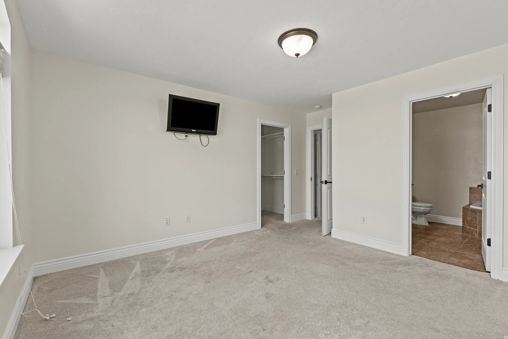 Carpeted interior space with light-toned walls, white trim, and a ceiling-mounted light fixture