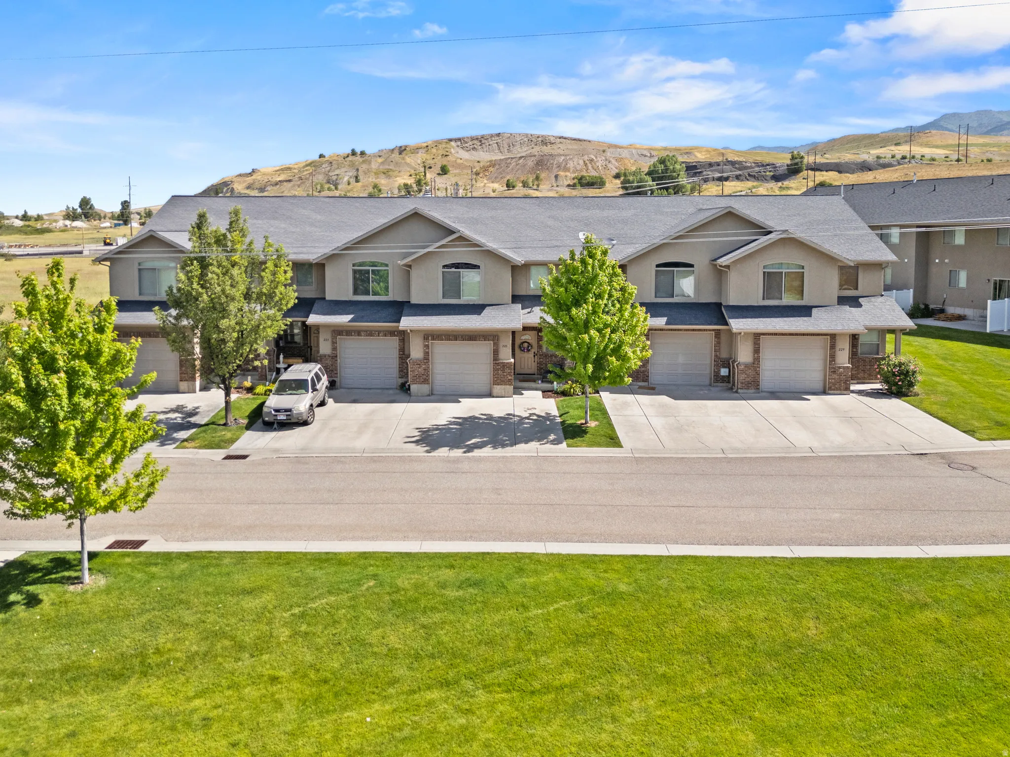 Multi-unit residential structure featuring a gray shingle roof and light-colored stucco siding