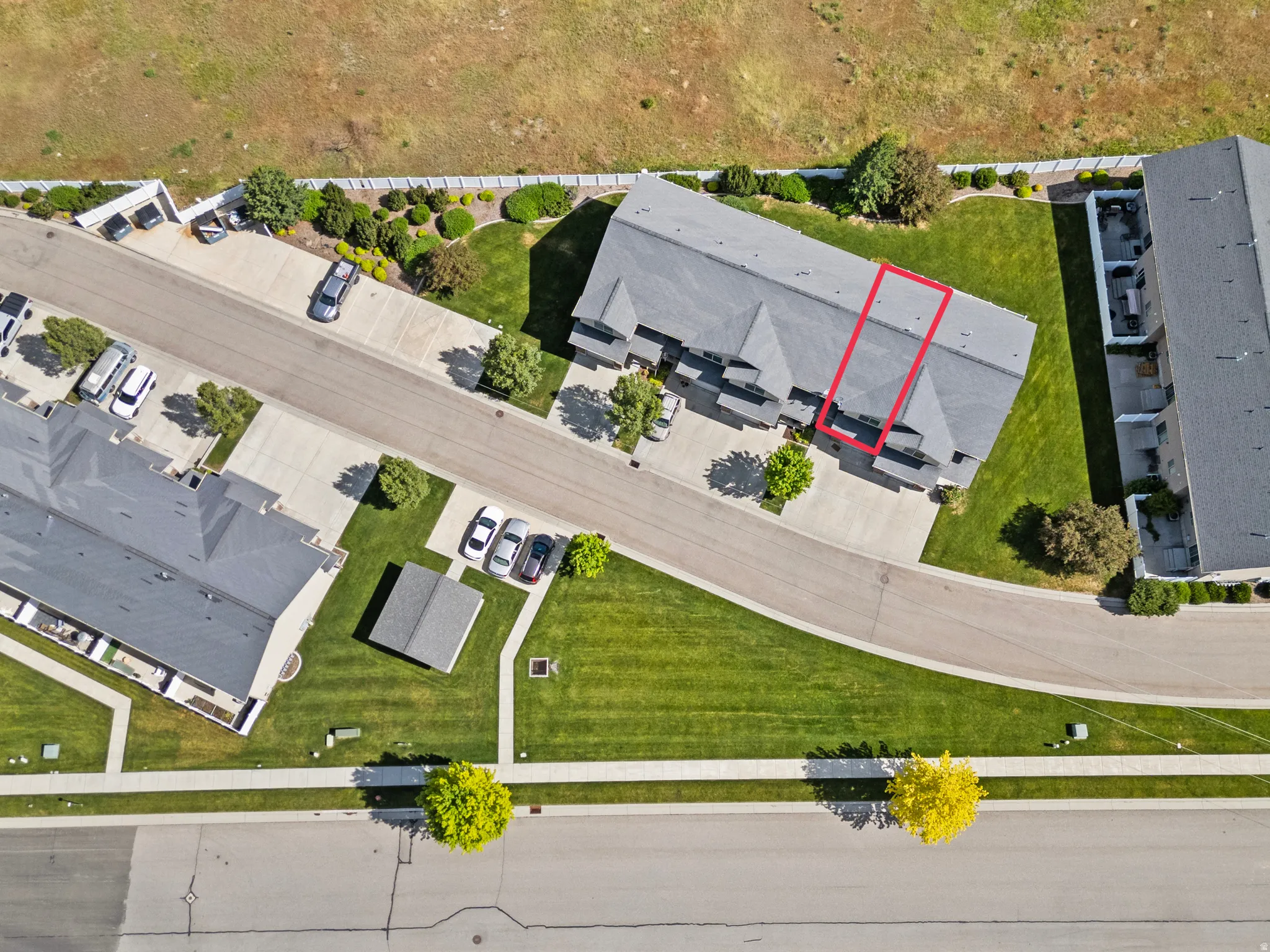 Aerial representation of a residential townhome unit featuring a dark shingled roof, a private patio space, and dedicated parking