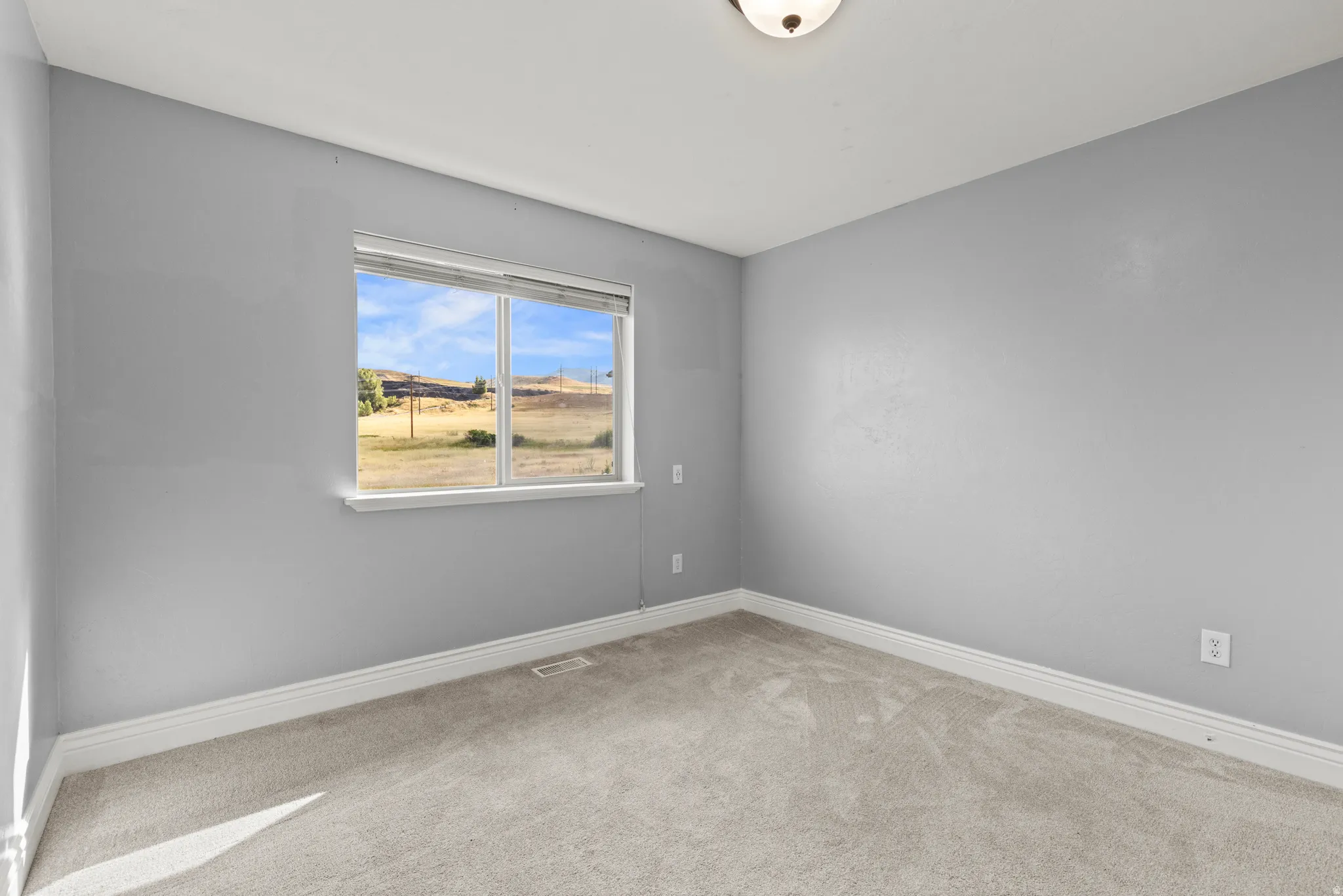 Neutral grey walls with white trim and a single window offering exterior scenery