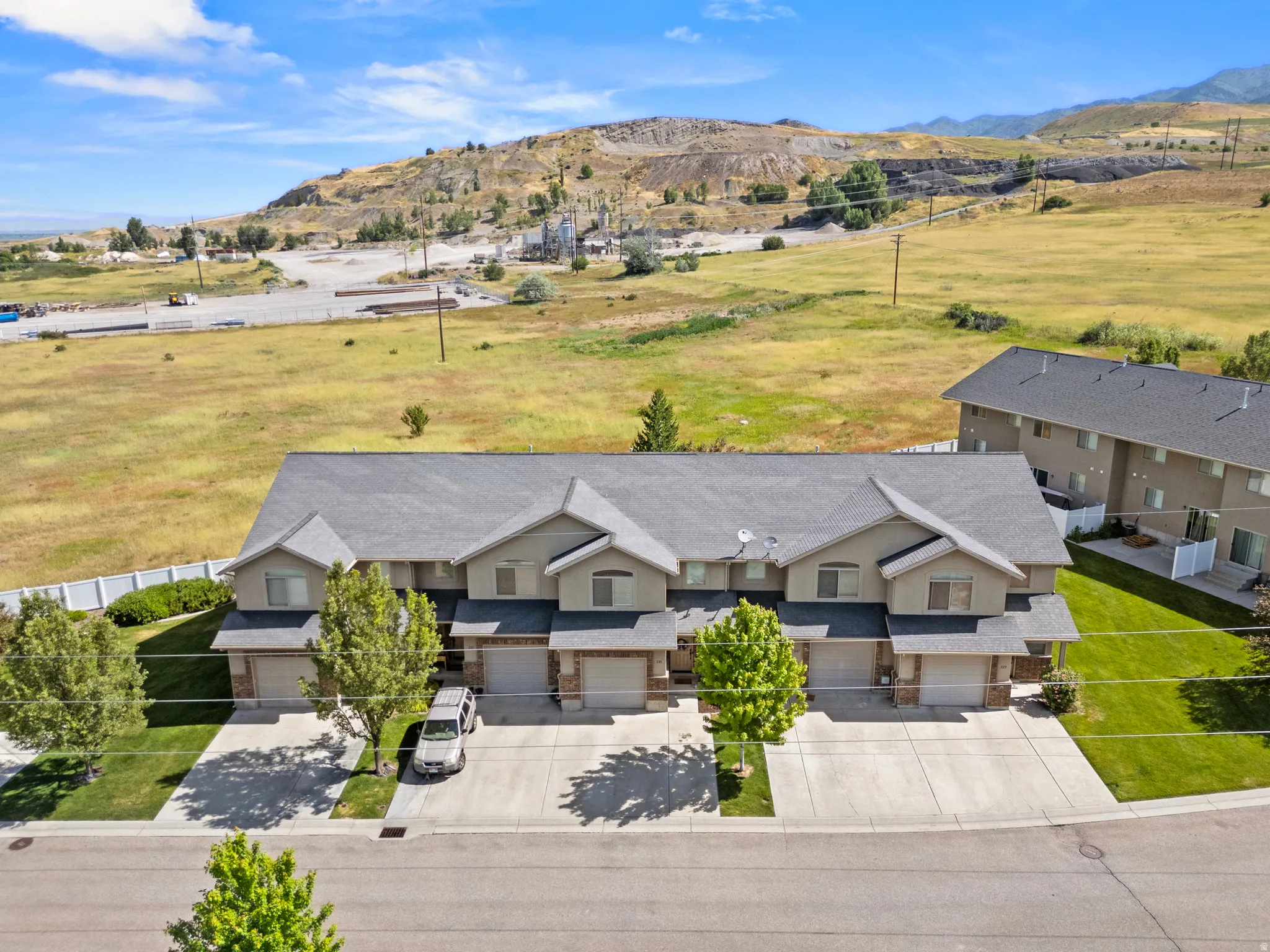 Townhome-style residences featuring light-colored stucco exteriors, attached garages, and individual driveways