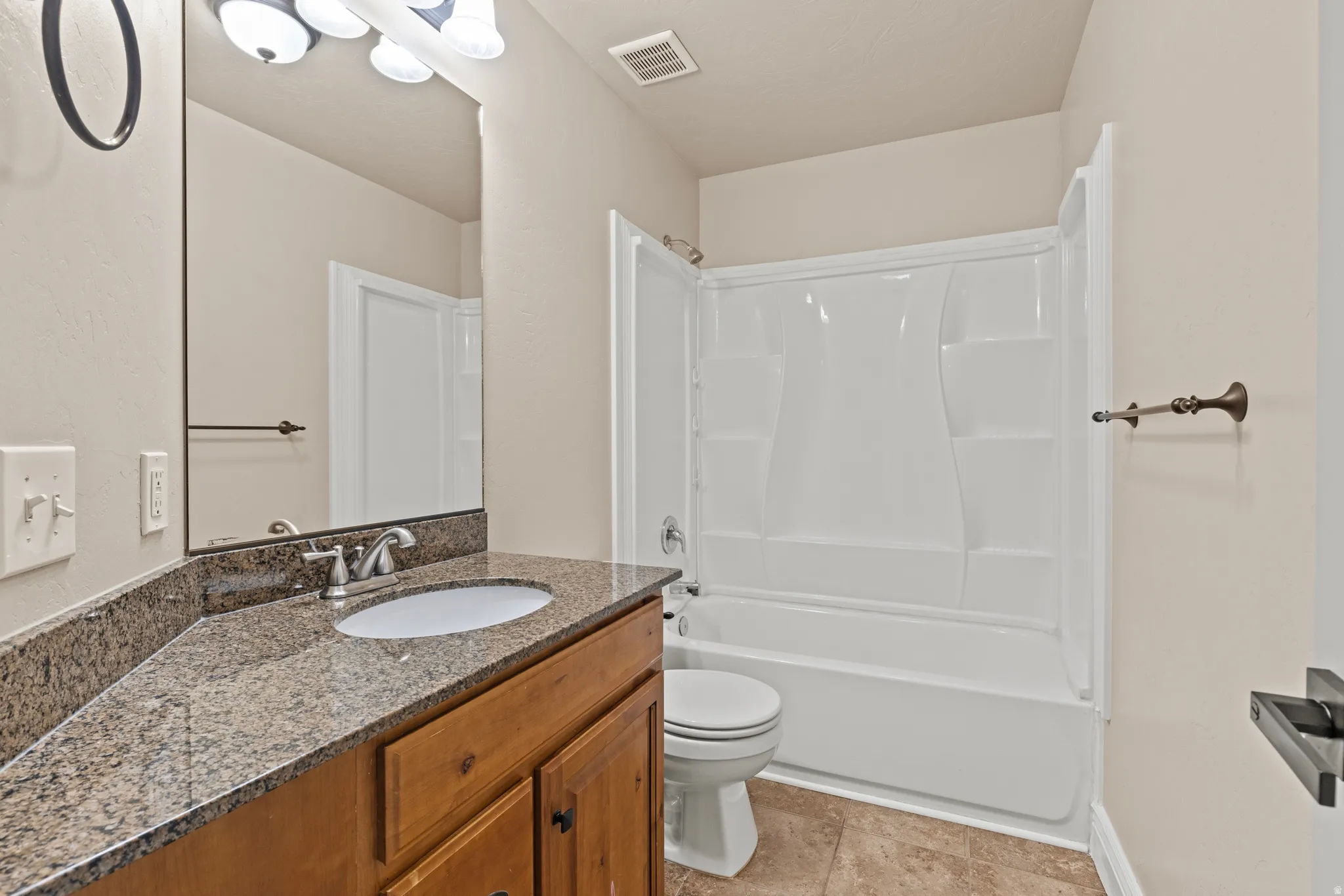 Bathroom featuring a wood-finish vanity with a granite countertop and an undermount sink