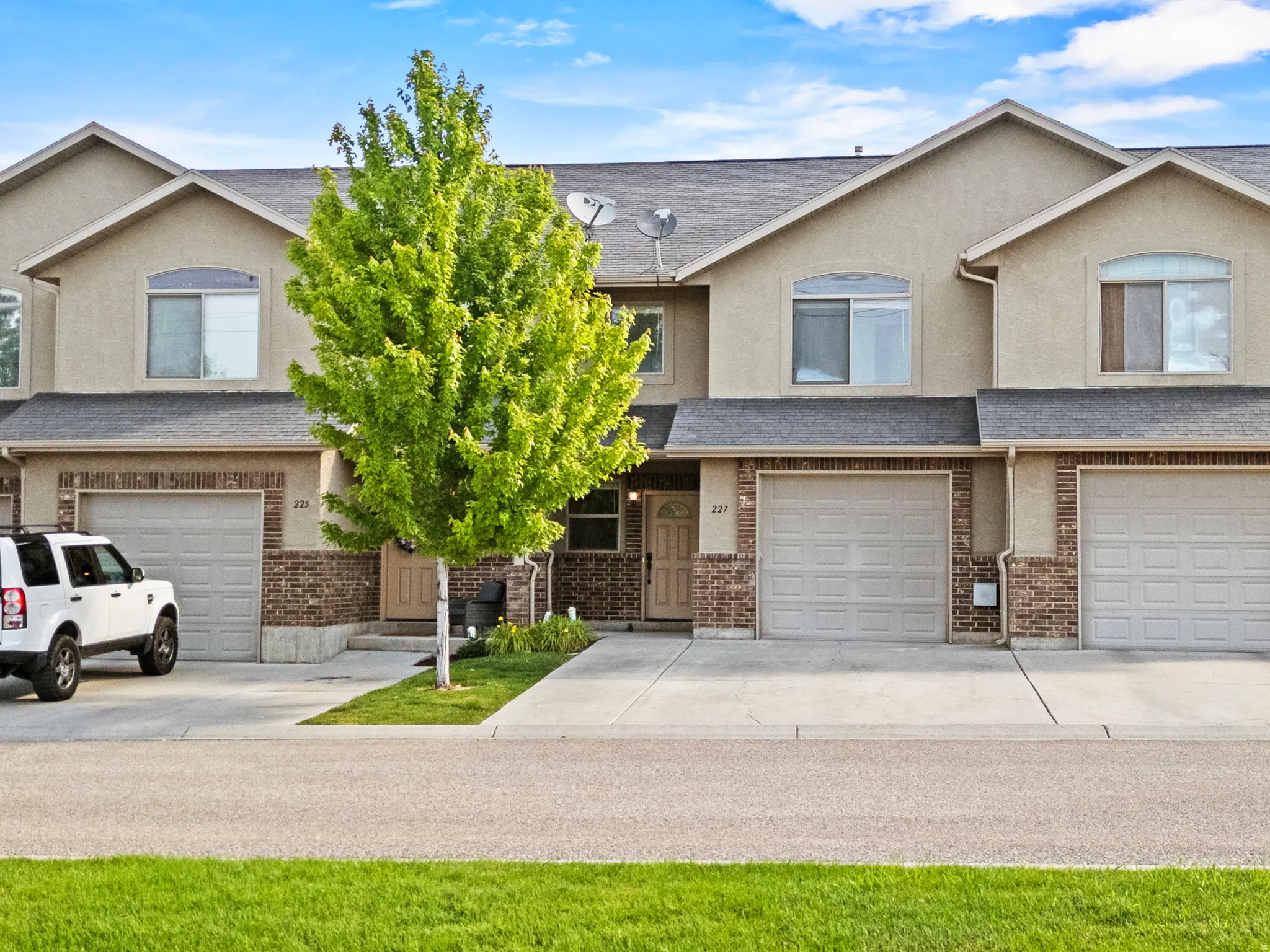 Townhome exterior featuring tan stucco siding and brick veneer accents