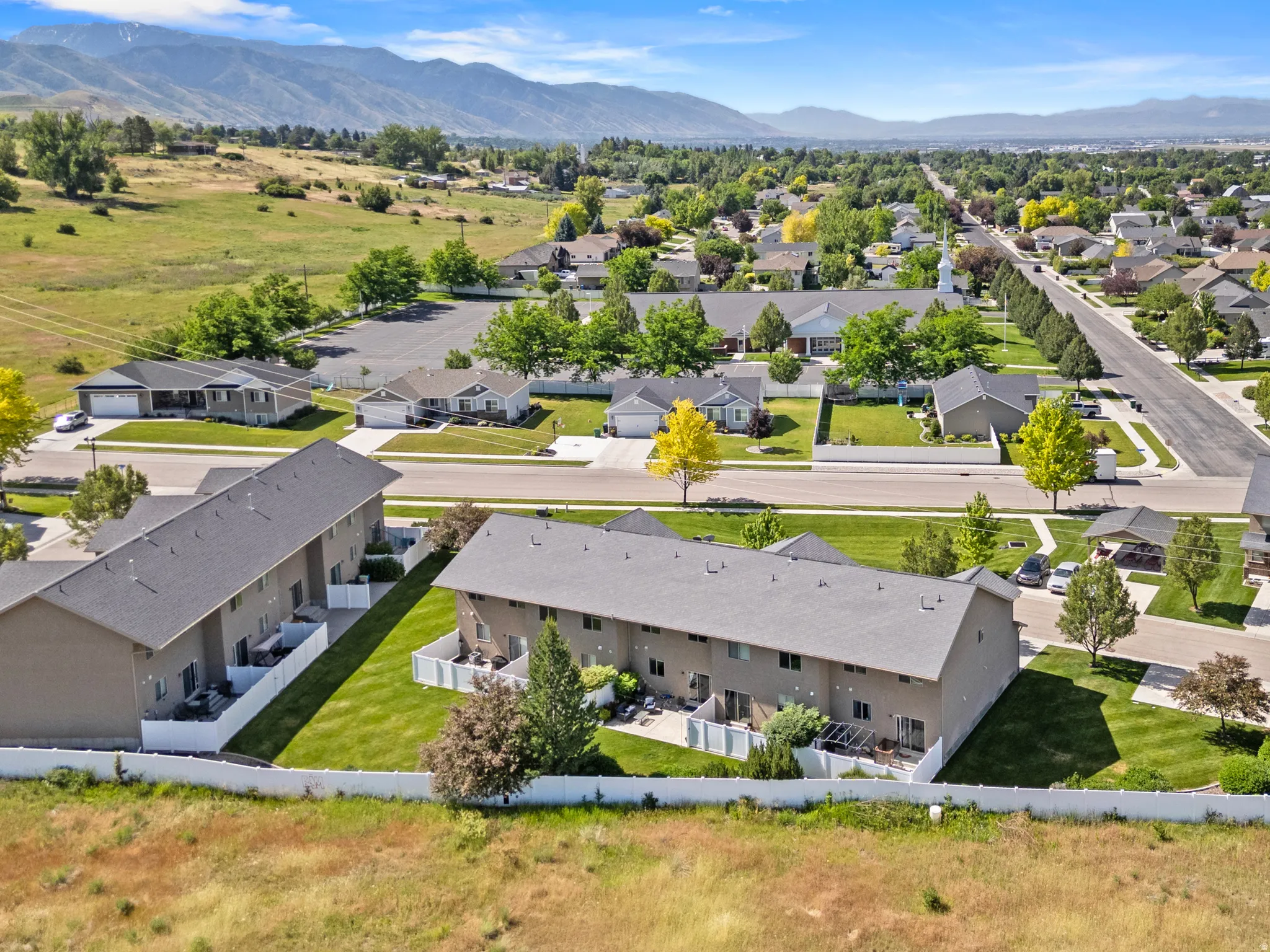 Aerial perspective showcasing multiple properties with dark gray roofs and tan exteriors