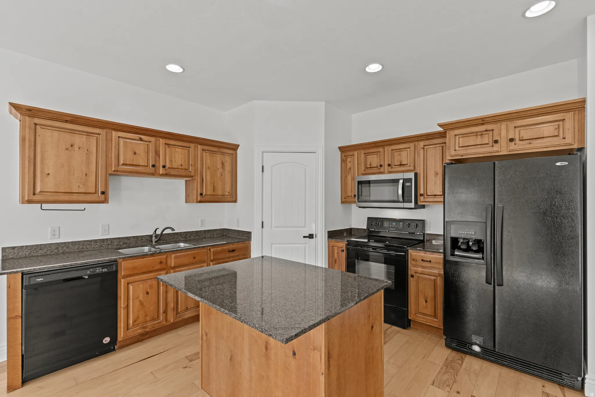 Kitchen featuring wood-finish cabinetry, granite countertops, and black appliances