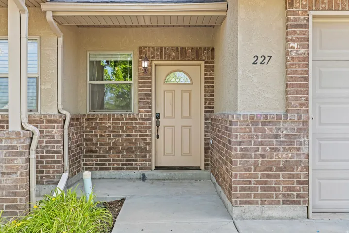 Entryway featuring a stucco and brick facade with a beige door, transom window, and exterior lighting fixture