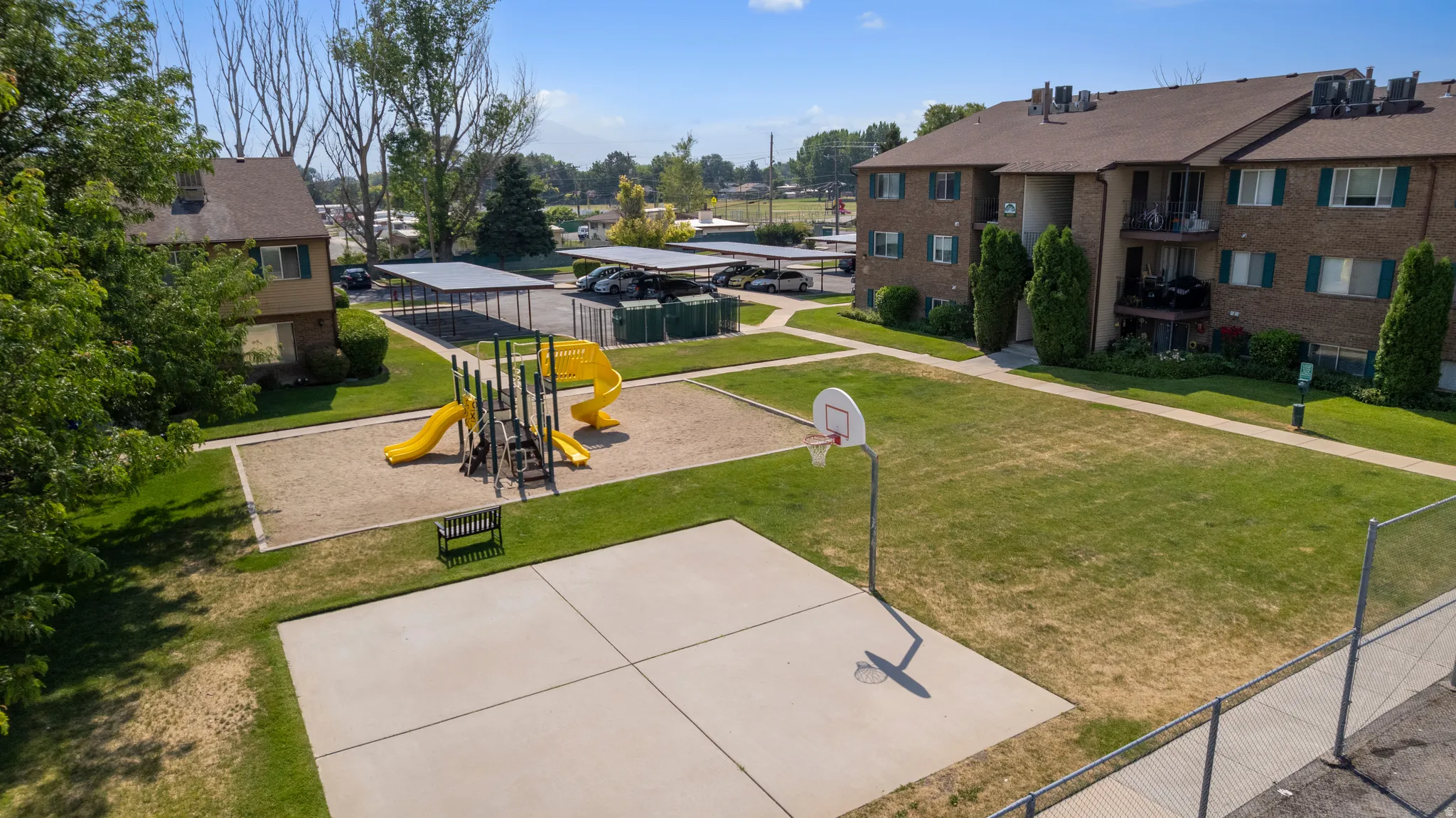 Community grounds featuring a basketball court, playground with slides, and green spaces