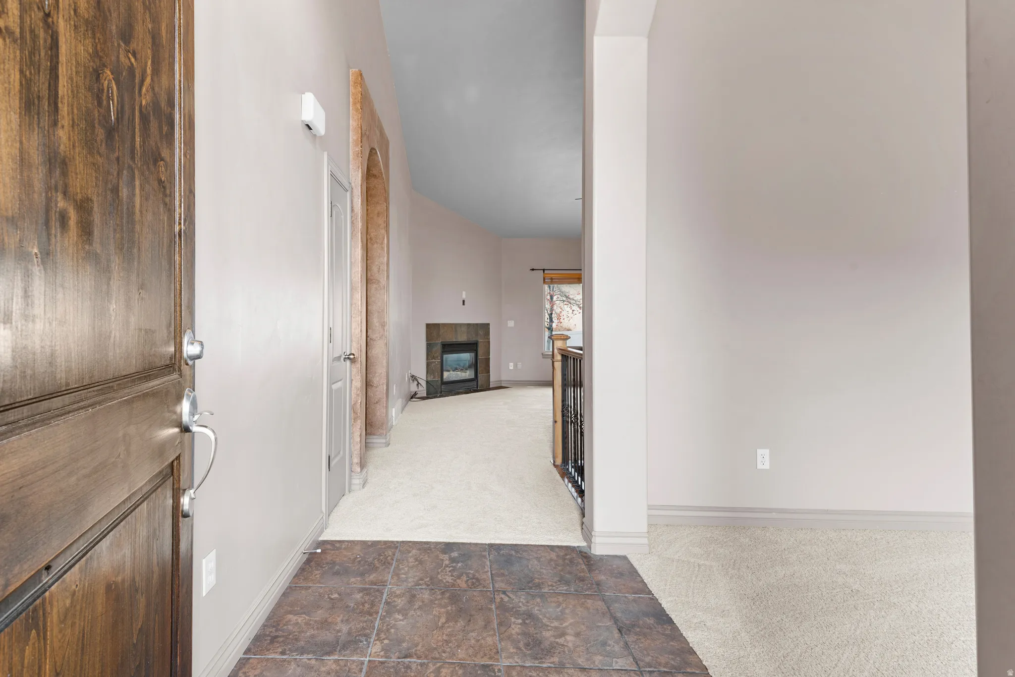 Entryway featuring a rich wood-paneled door, square tile flooring, and light-toned walls