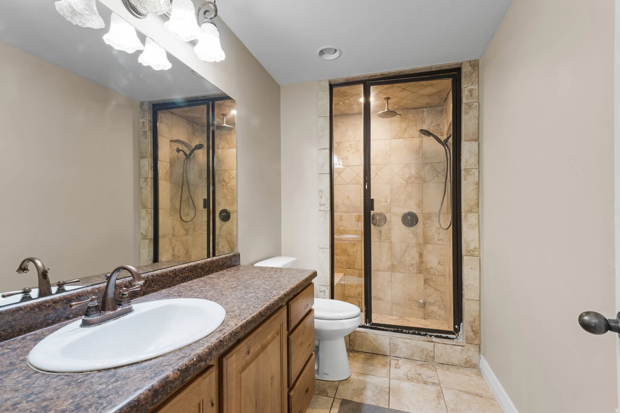 Bathroom featuring a walk-in shower with tiled walls, dual shower heads, and a dark framed glass enclosure