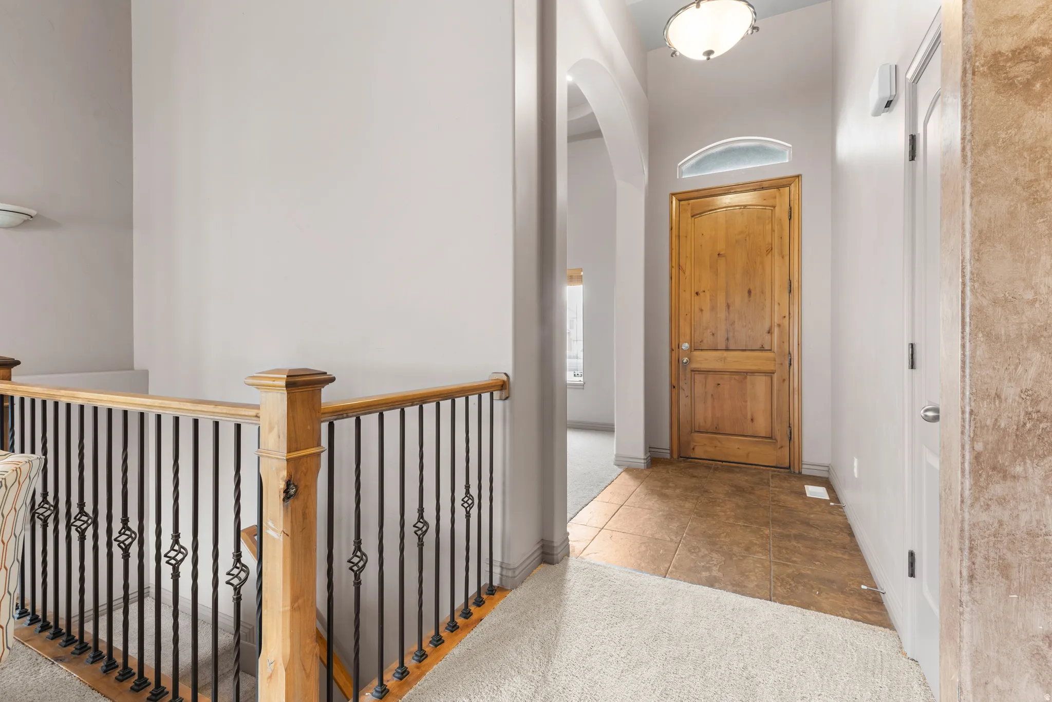 Entryway featuring a wood-panel door with an arched transom, recessed arched ceiling detail, and ceiling-mounted light fixture