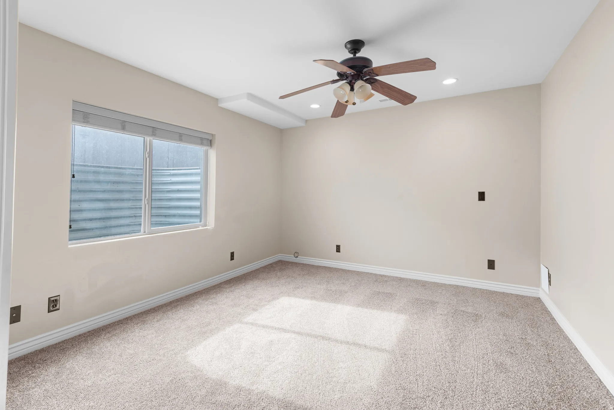 Neutral-toned carpeting and walls complement a ceiling fan with integrated lighting