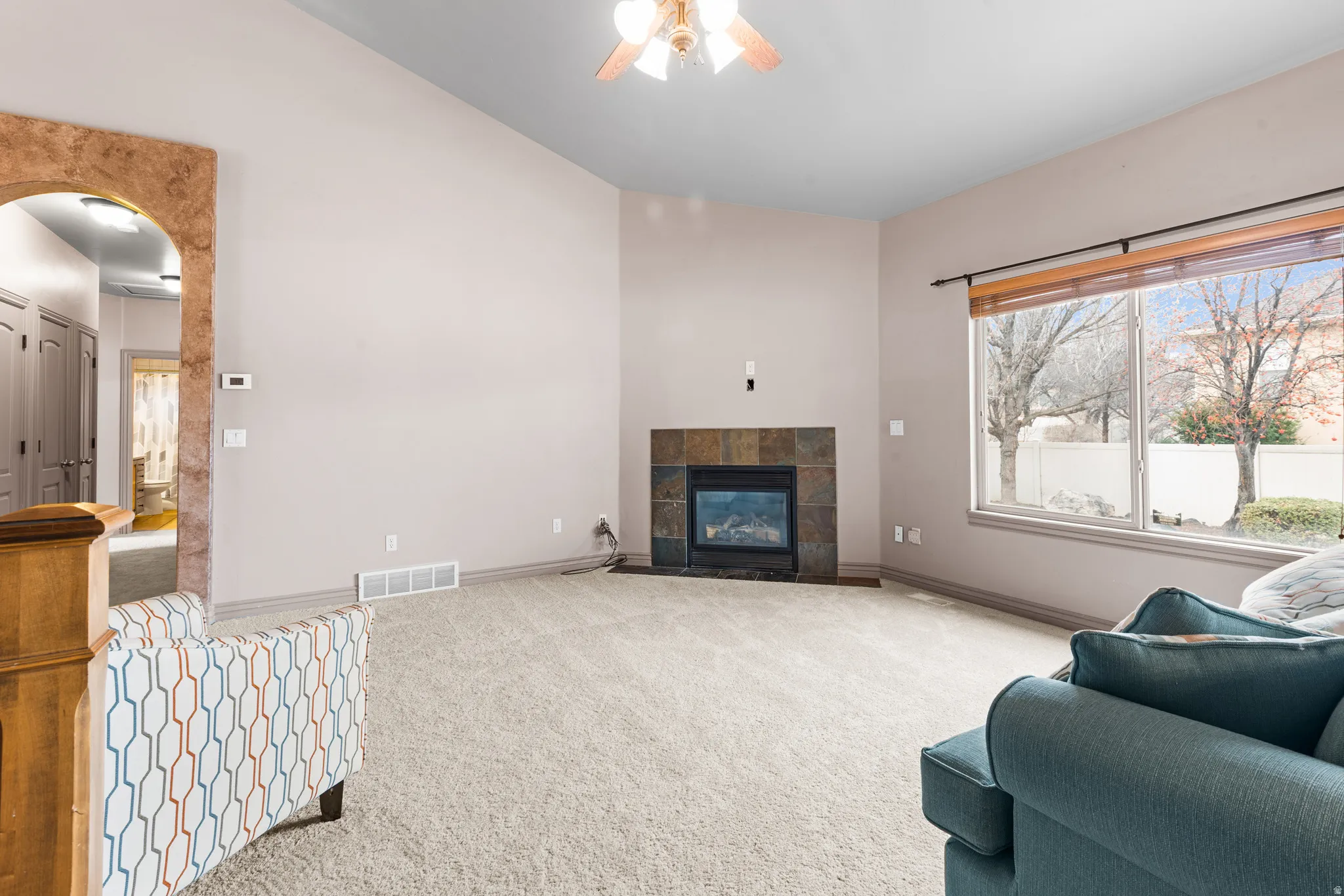 Spacious living area featuring a vaulted ceiling and a stone-tile fireplace with an integrated firebox