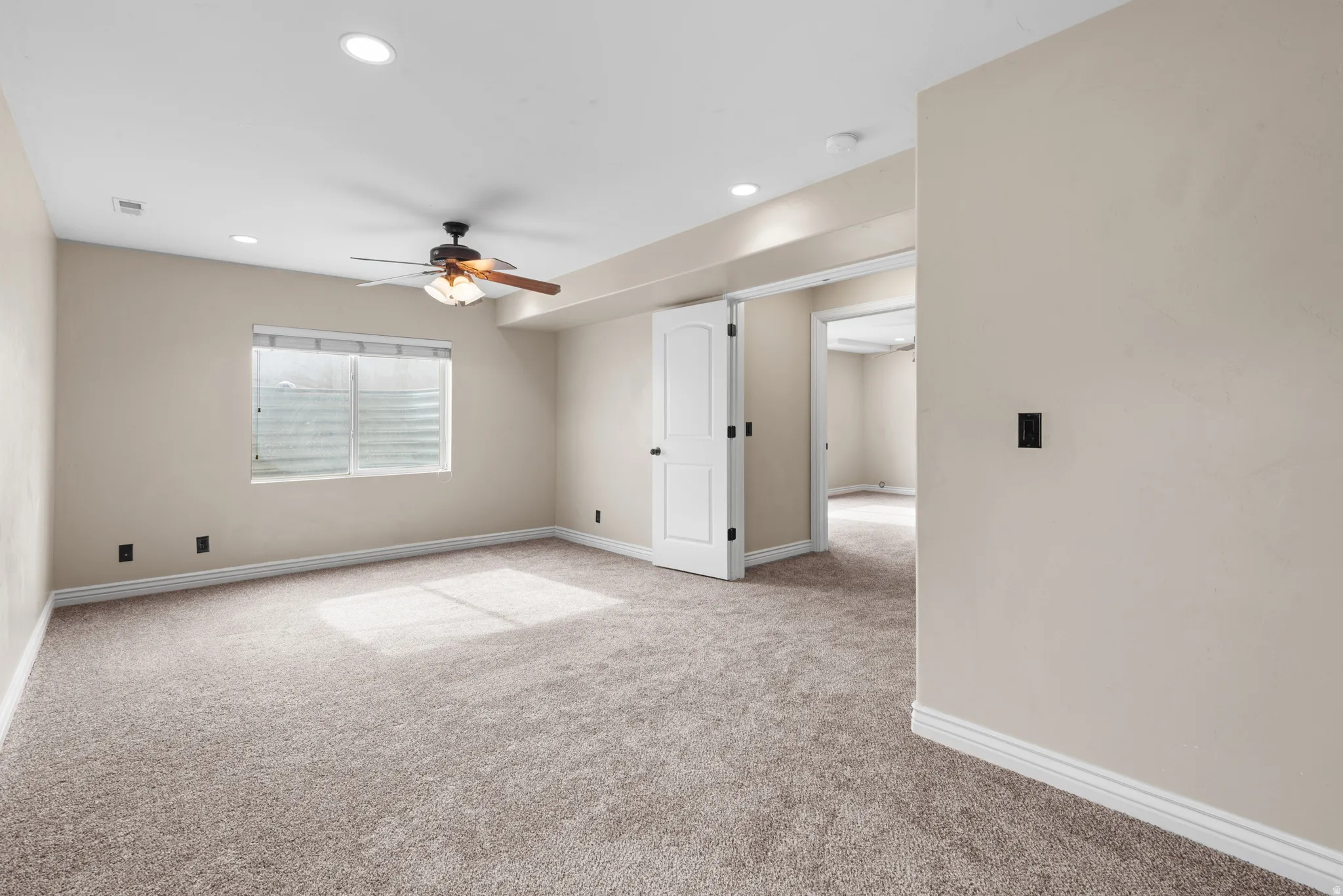 Carpeted room featuring a ceiling fan with integrated lighting, recessed lighting, a window with horizontal blinds, and a white interior door