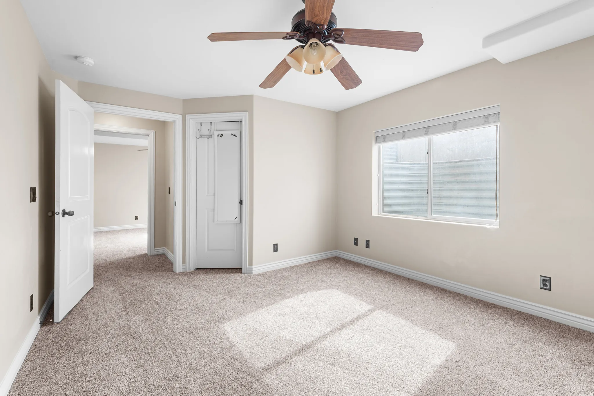Carpeted room featuring a ceiling fan with integrated lighting, a window with blinds, and white trim throughout