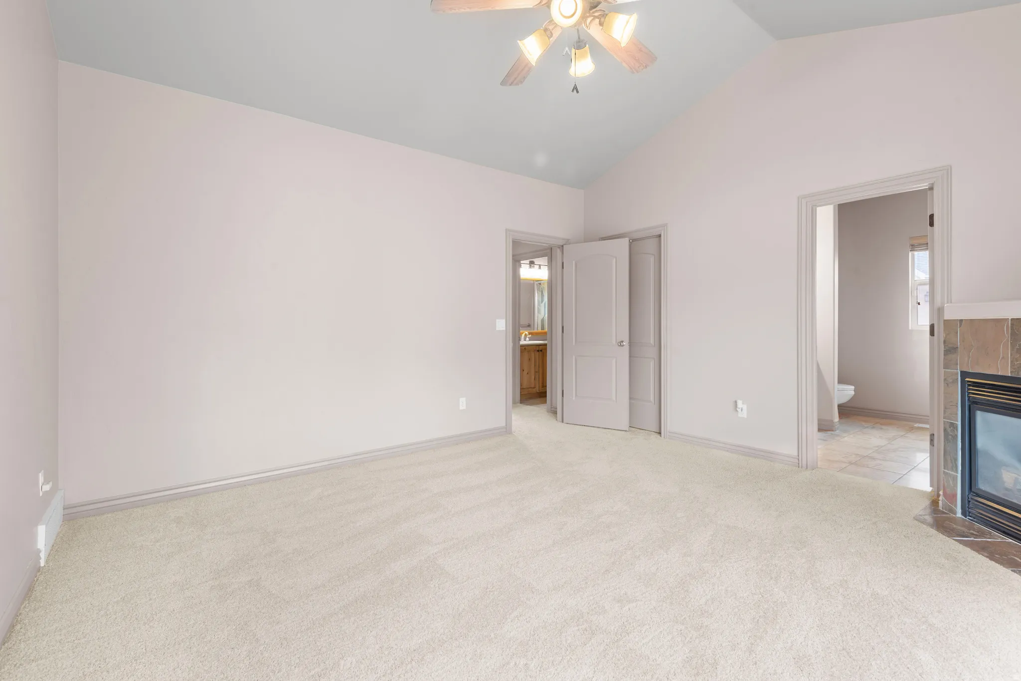 Carpeted room featuring a vaulted ceiling and a ceiling fan with integrated lighting