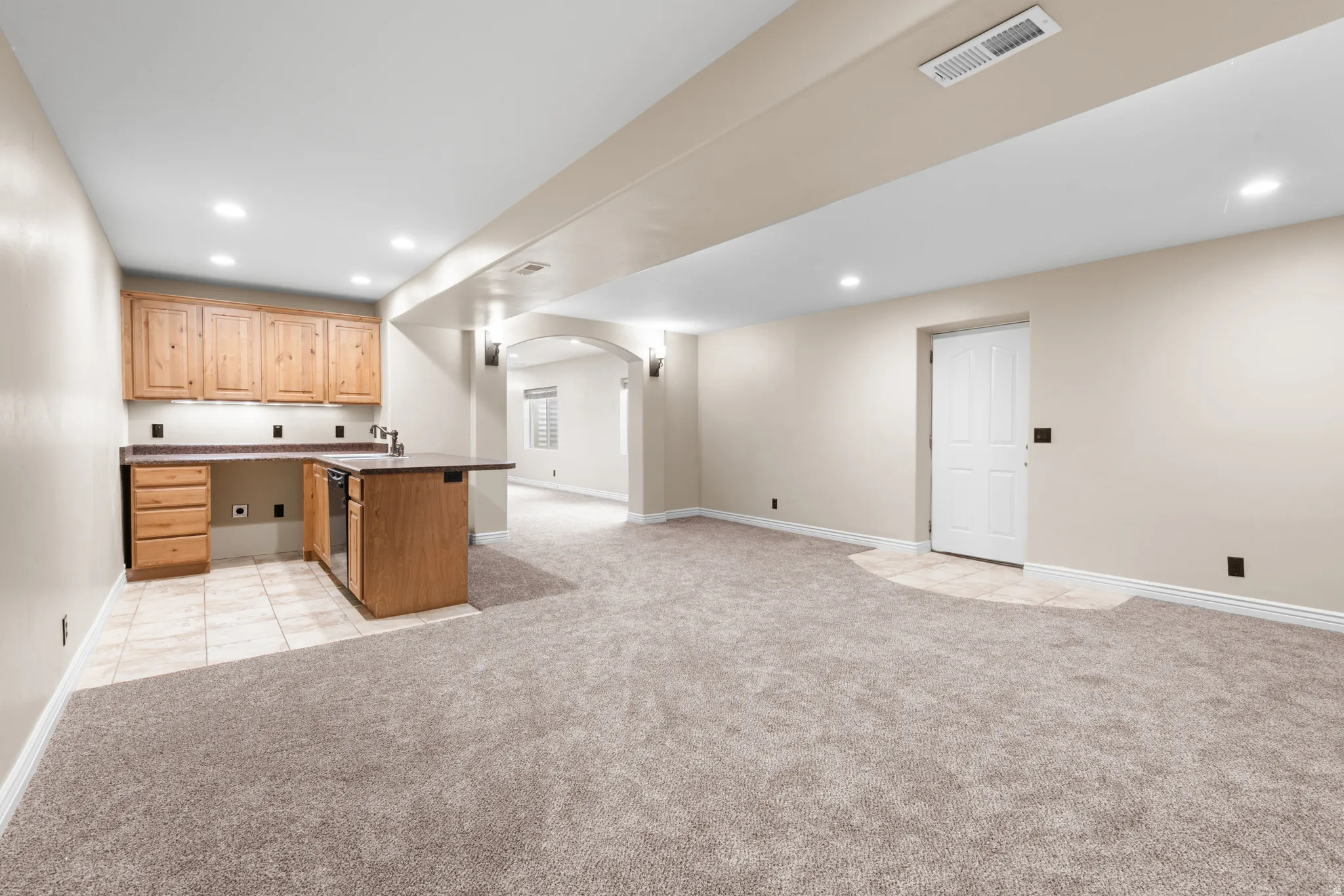 Open concept lower level featuring a wet bar with wood cabinetry, a built-in beverage refrigerator, and countertop space