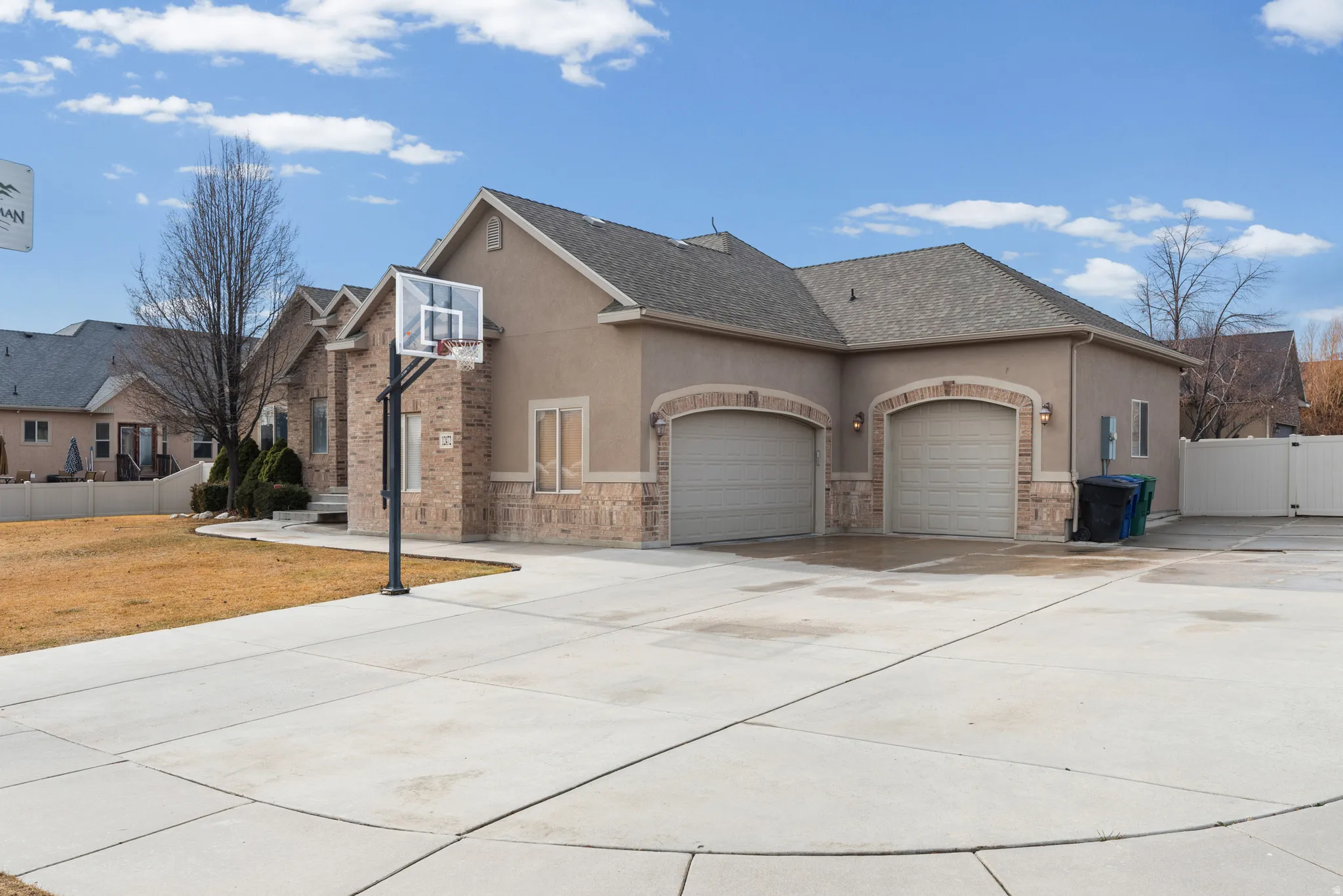 Stucco exterior with brick accents and a multi-car concrete driveway