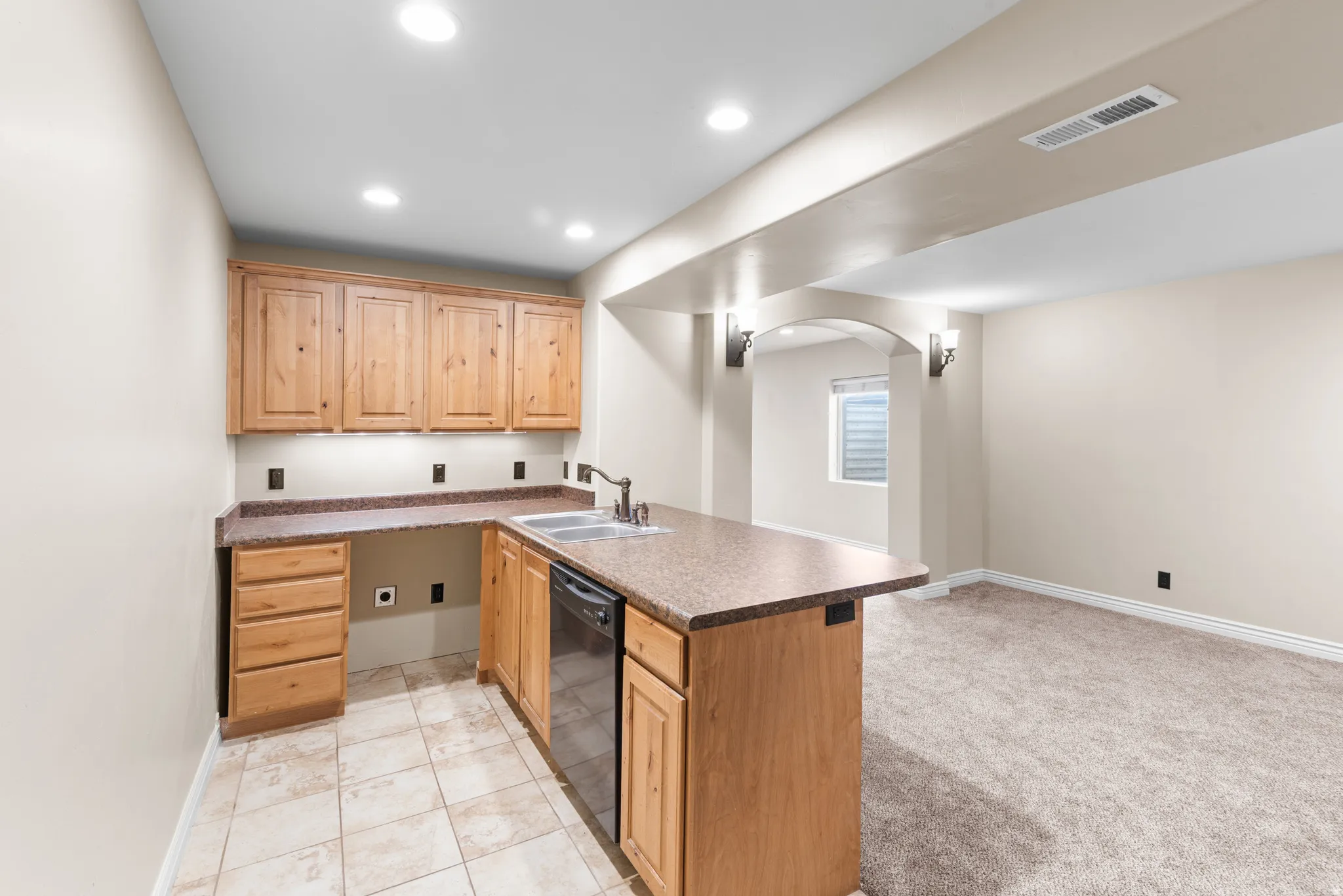 Kitchenette with wood cabinetry, integrated sink, and dishwasher