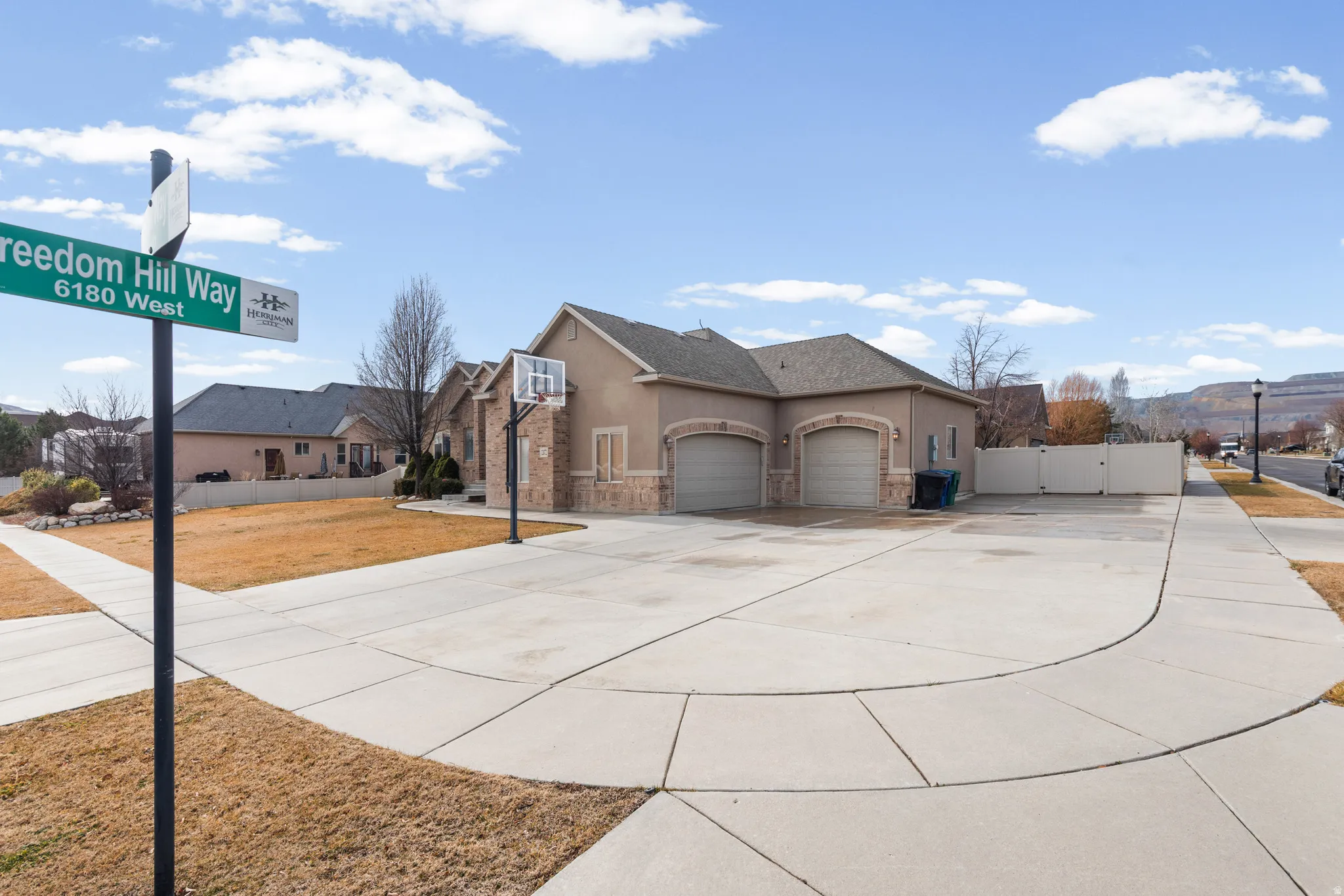 Exterior featuring a stucco finish with stone accents, a multi-car garage with arched entrances, a concrete driveway, and a fenced side yard