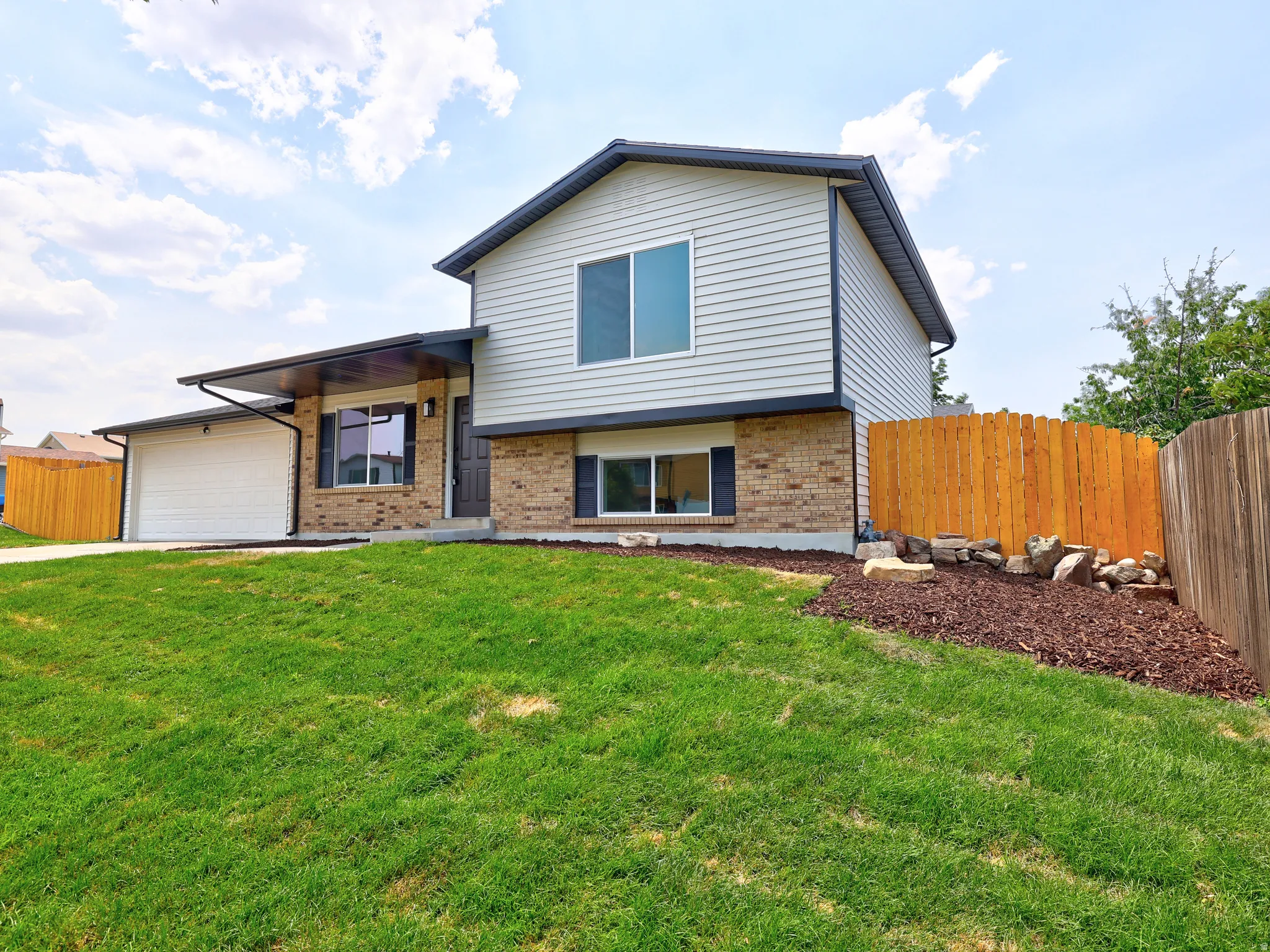 Split-level residence featuring light gray siding and brick accents