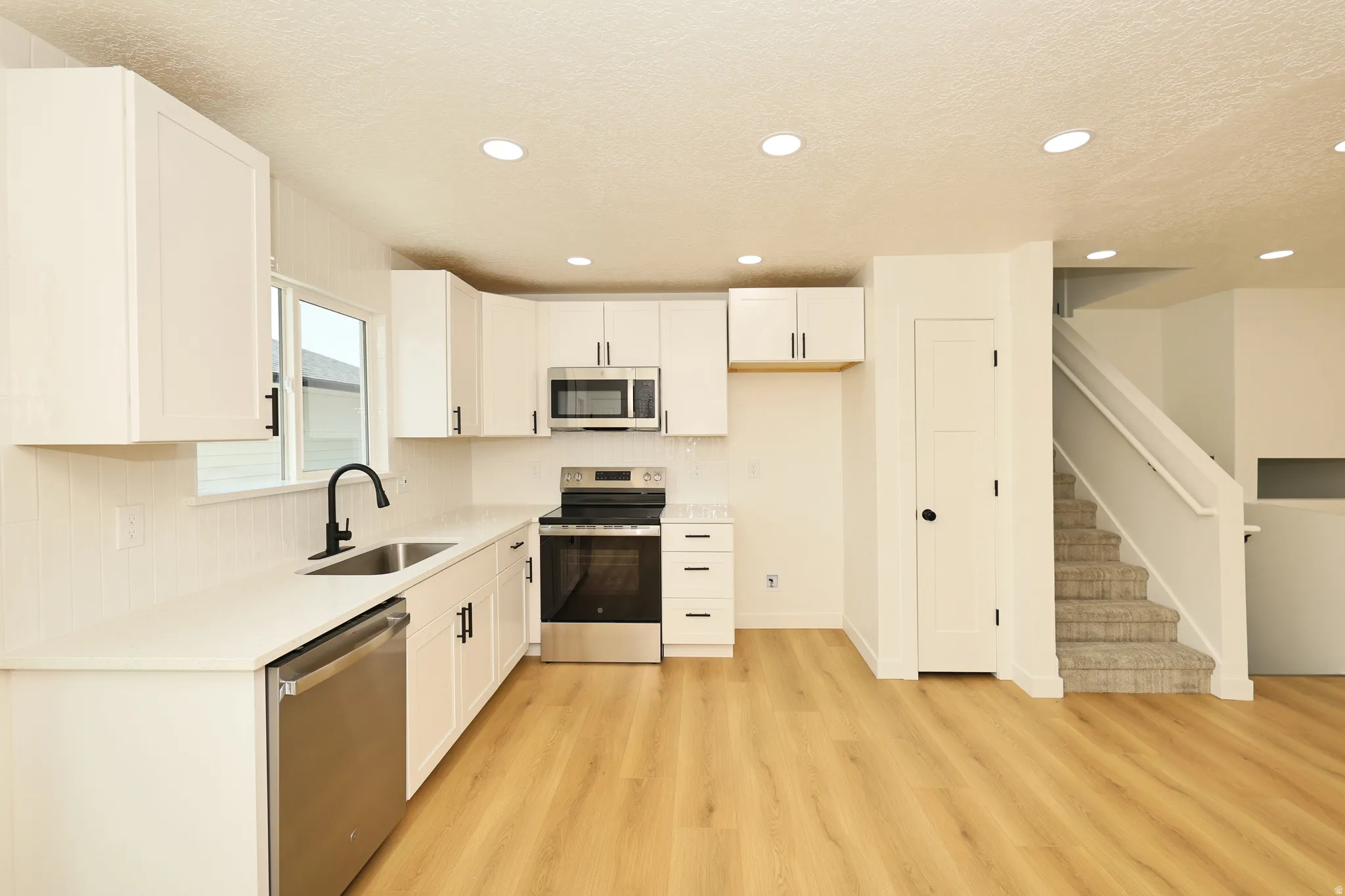 Kitchen with white cabinetry, stainless steel appliances, and light countertops