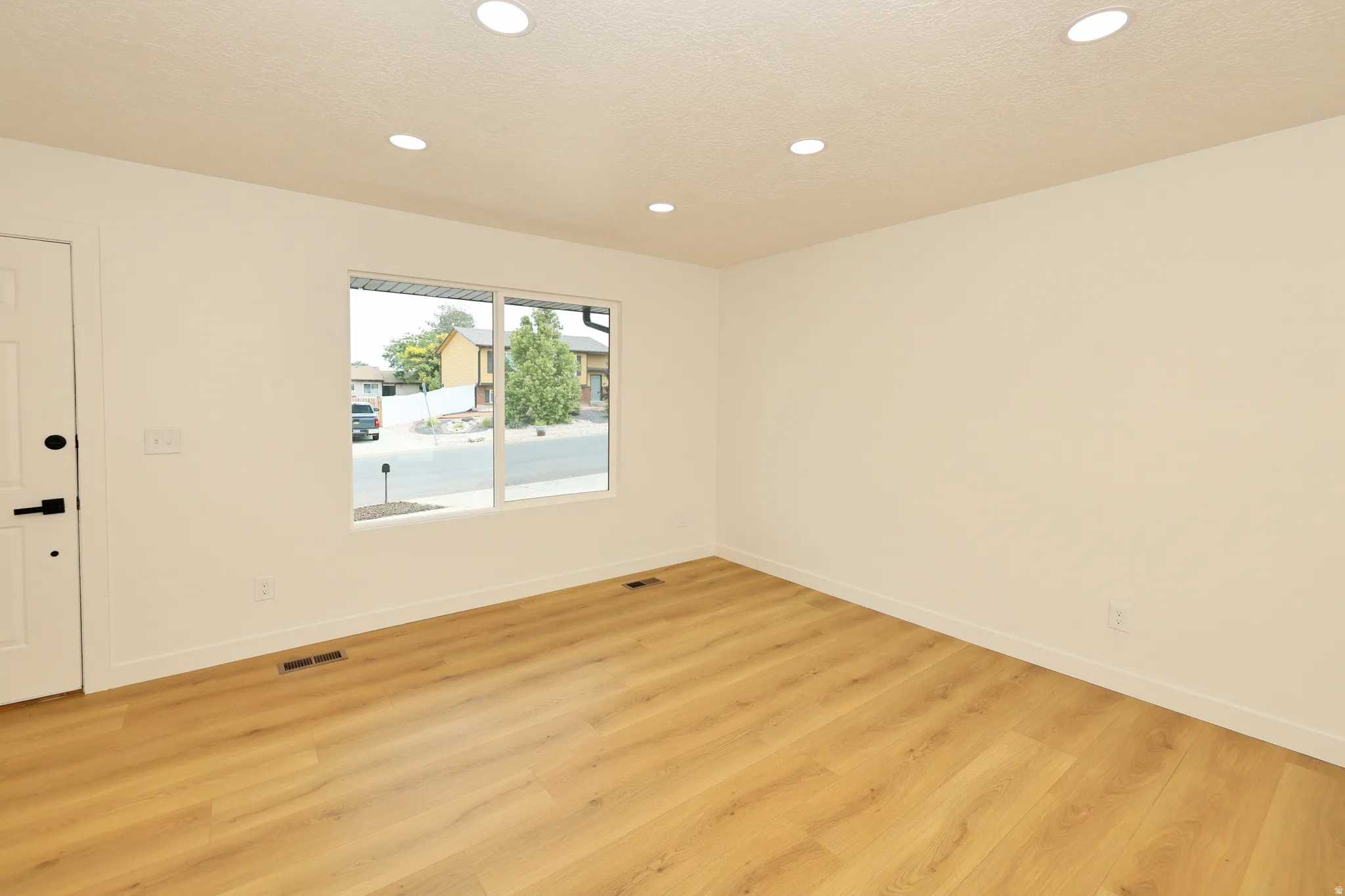 Room featuring wood-finish flooring, recessed lighting, and a multi-pane window