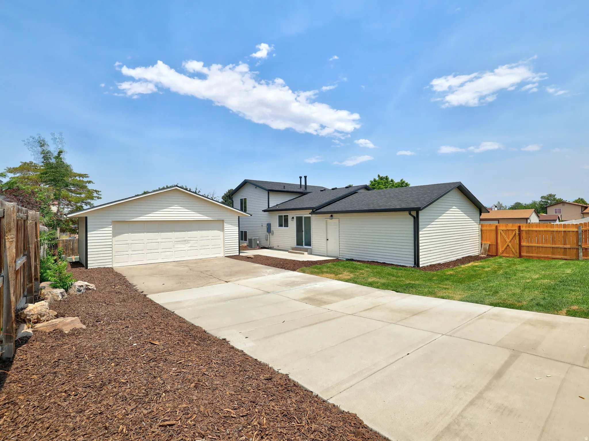 Spacious concrete driveway servicing a detached two-car garage and additional storage structure
