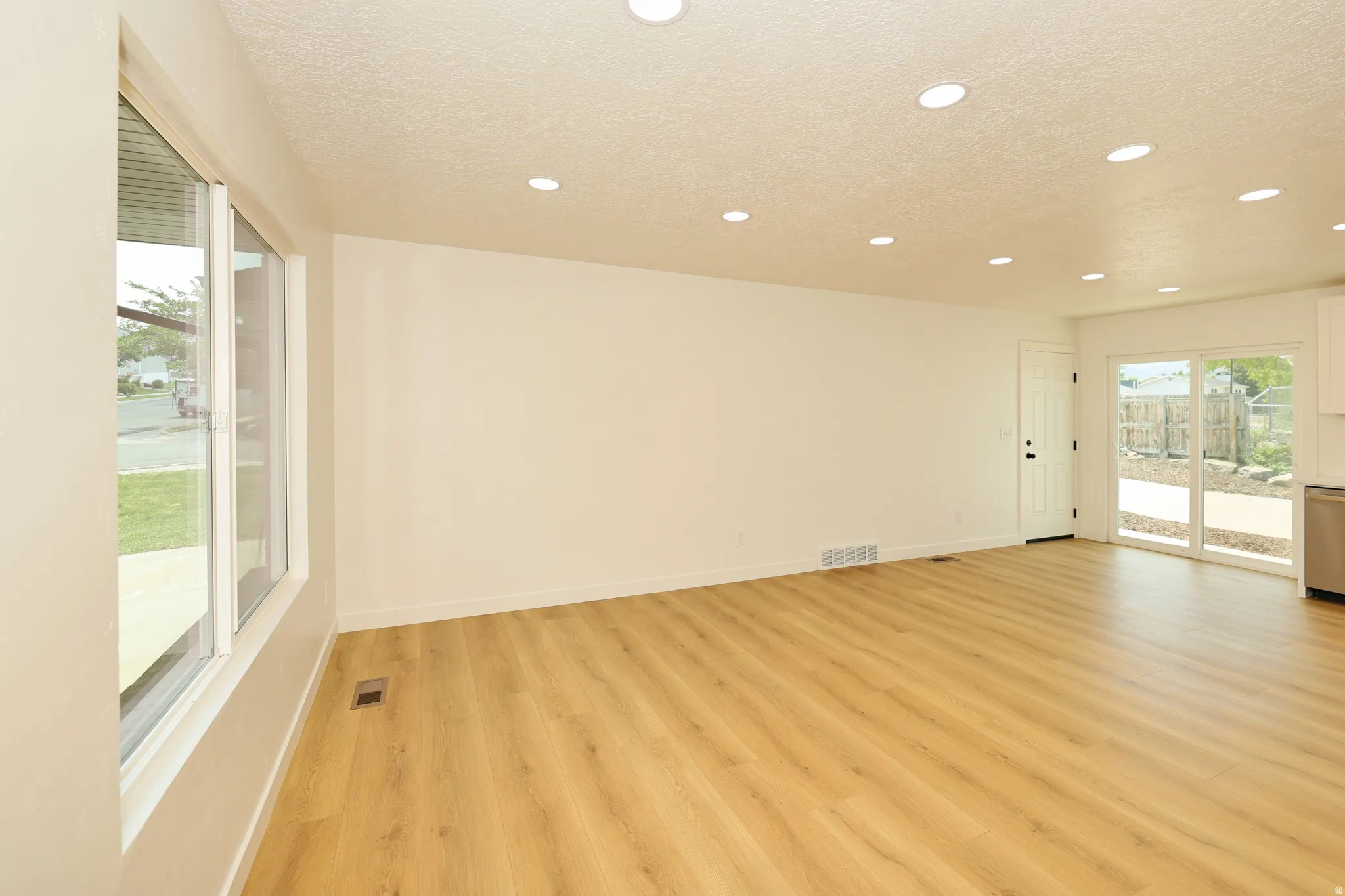 Spacious room featuring light wood-finish flooring, recessed lighting, and white walls