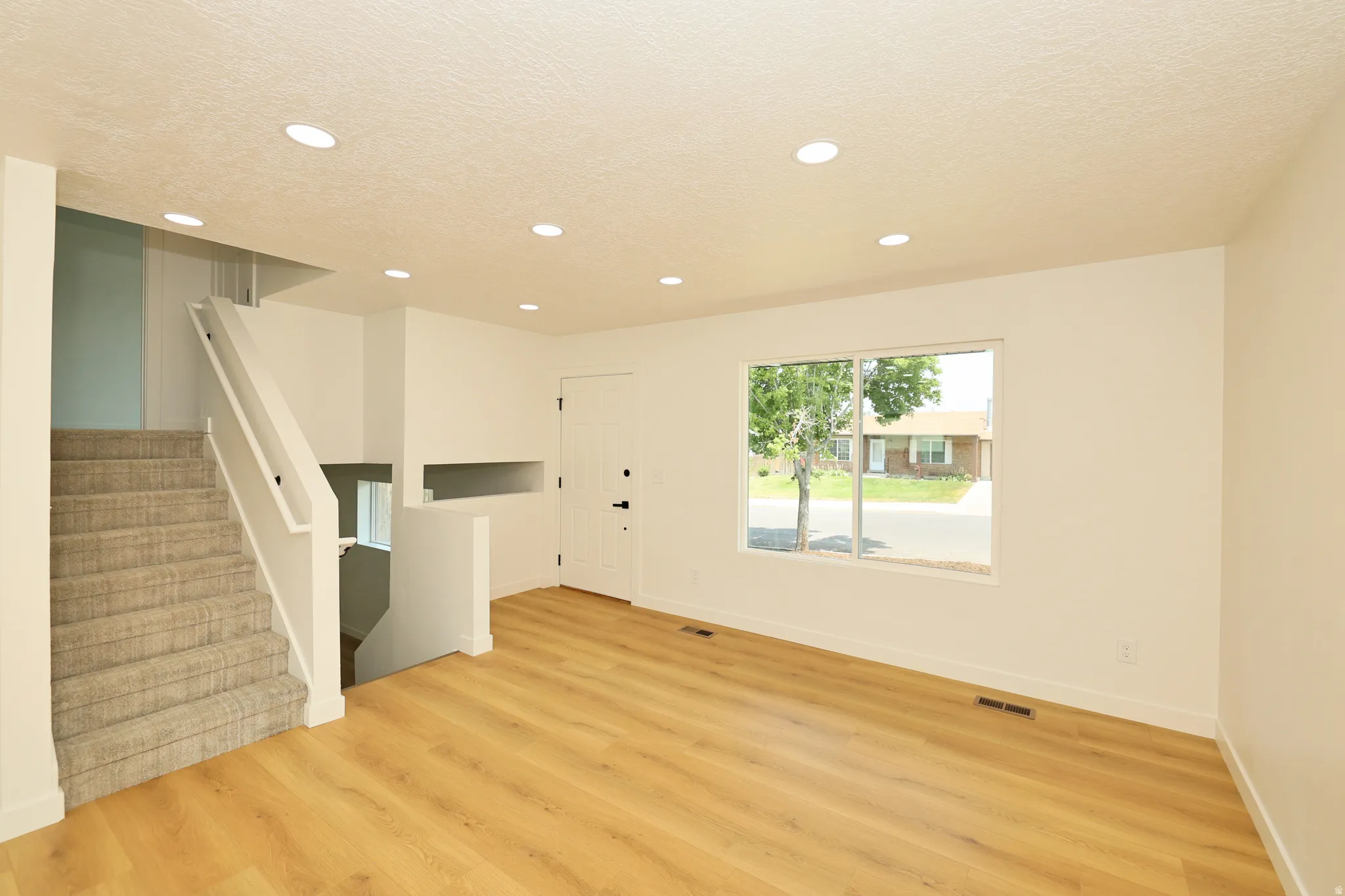 Spacious interior featuring wood-finish flooring, recessed lighting, and white baseboards