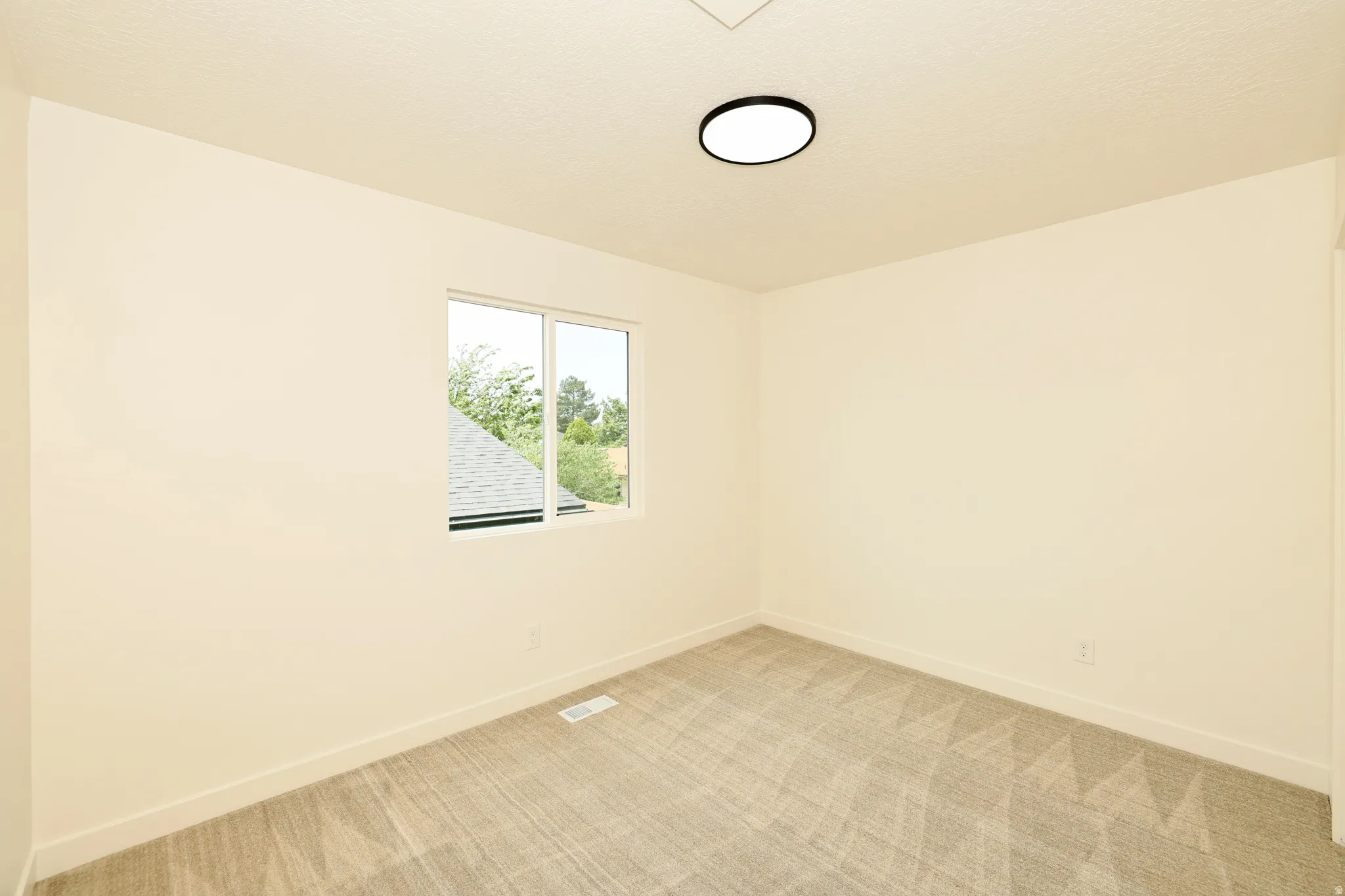 Room featuring neutral wall tones, patterned carpeting, a double-pane window, and a flush-mount ceiling light fixture