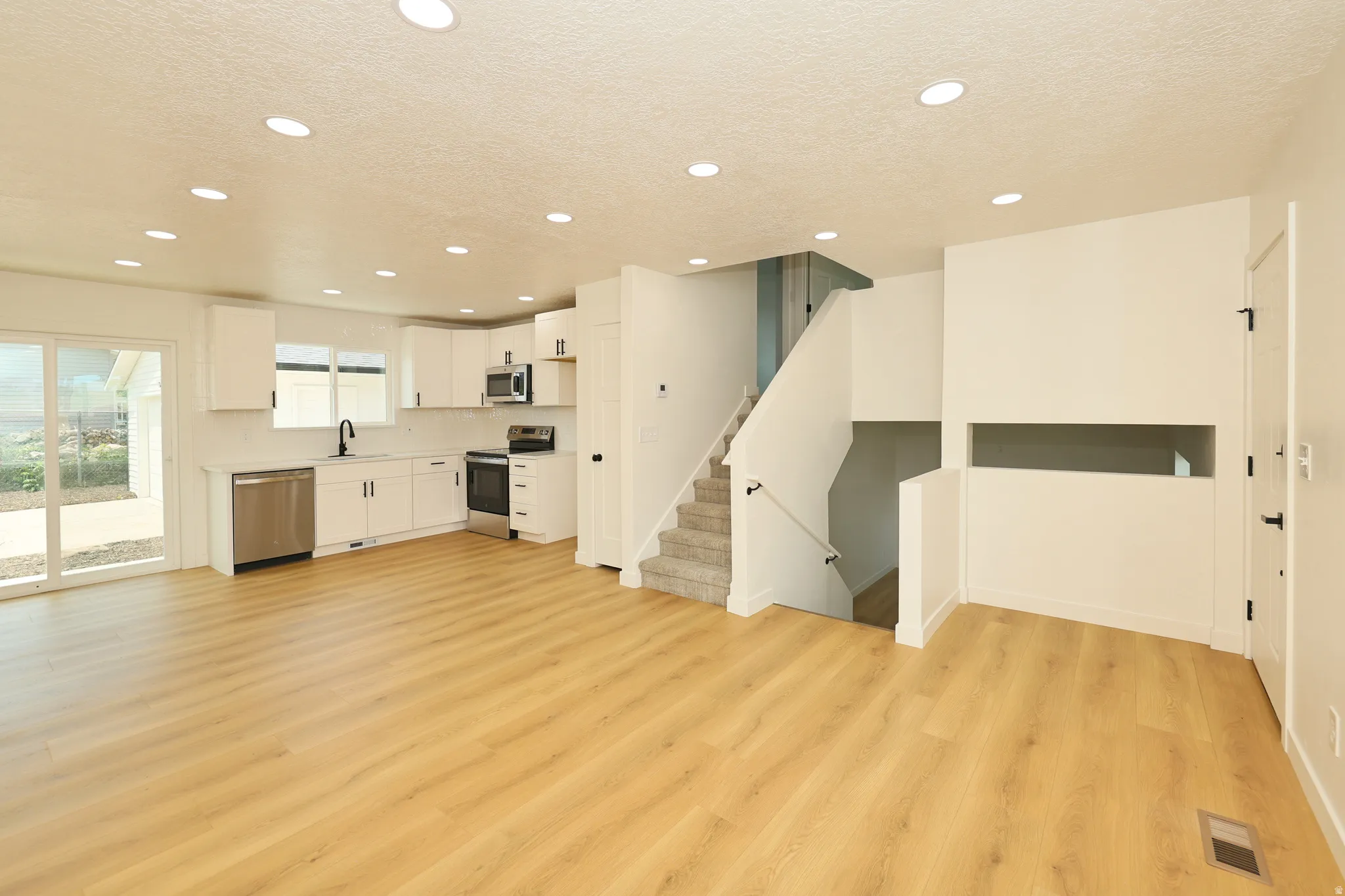Open-concept living area featuring wood-finish flooring, recessed lighting, and a contemporary kitchen