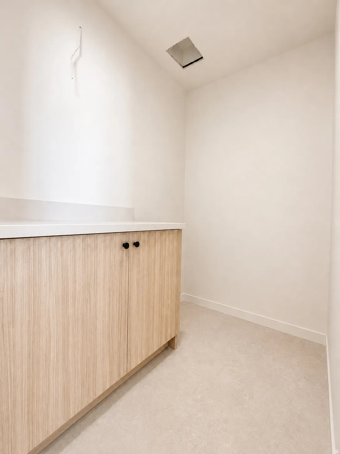 Modern utility space featuring custom wood-finish cabinetry with sleek hardware, white quartz countertop, and recessed ceiling lighting for optimal functionality and clean aesthetic appeal