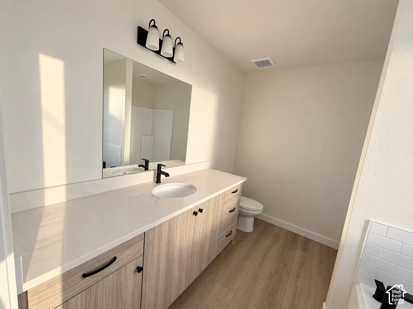 Contemporary vanity with wood-finish cabinetry, white countertop, and integrated sink