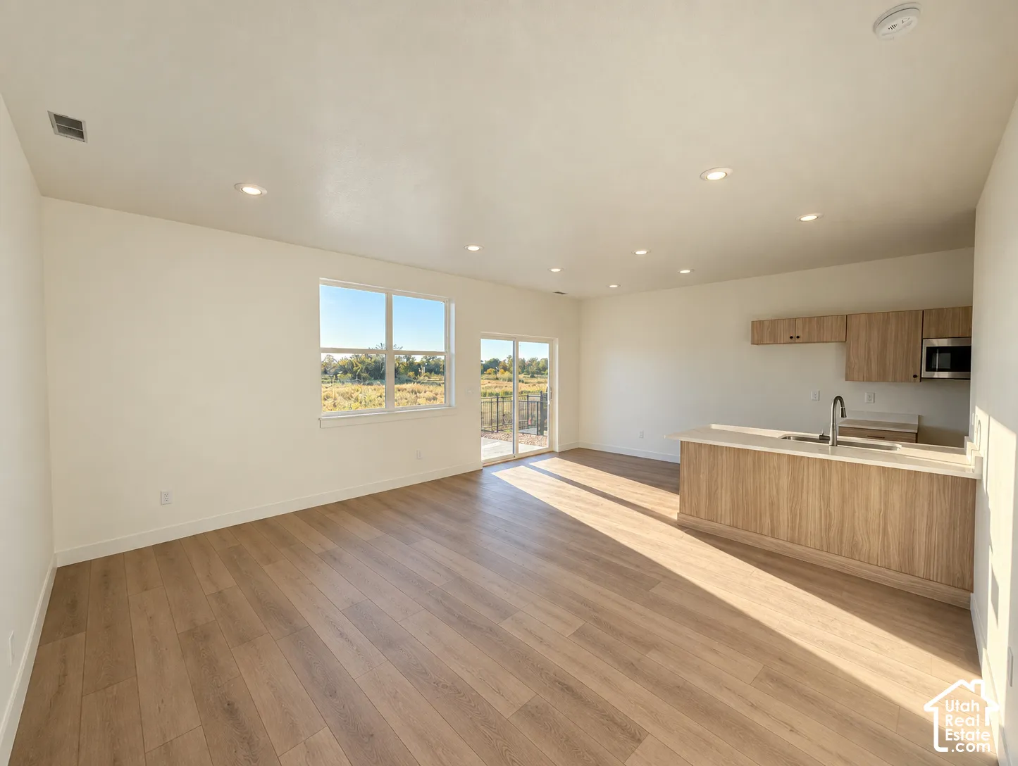 Open-concept living area featuring wood-finish flooring, recessed lighting, and a sliding glass door to an outdoor space